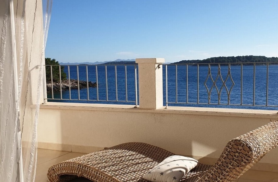 Terasa s výhledem na moře a relaxačním proutěným lehátkem.