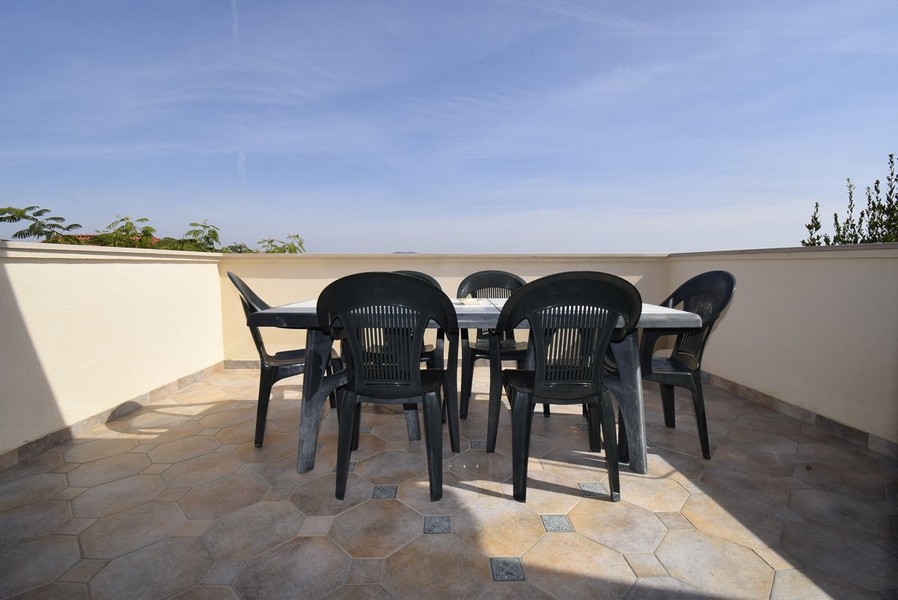 Prostorná, otevřená terasa s jednoduchými zahradními židlemi.