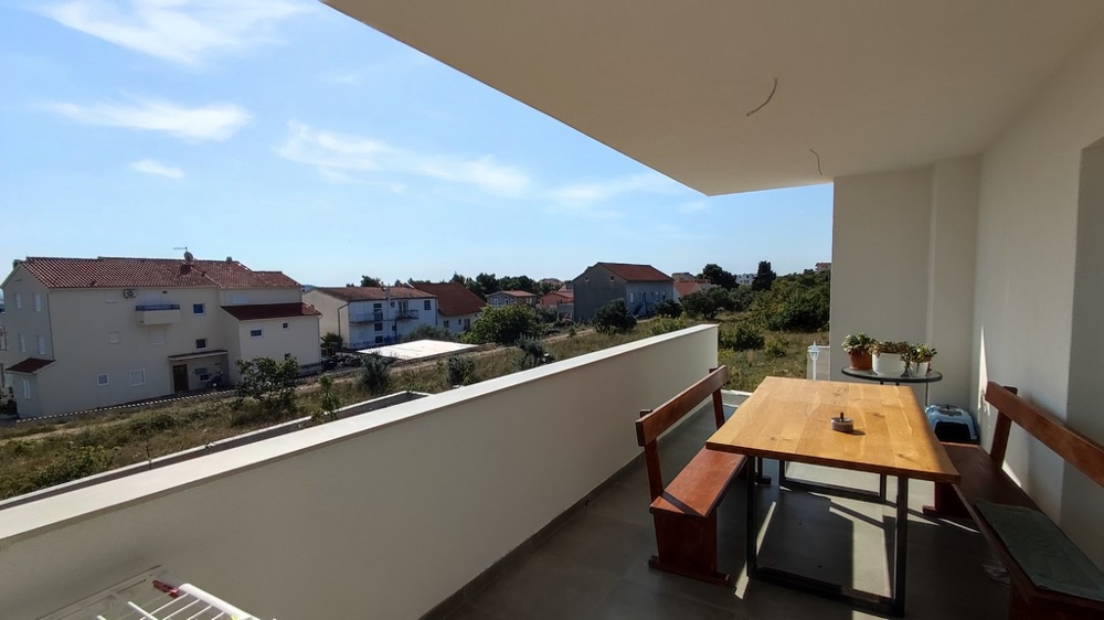 Prostorný balkon s jídelním koutem rodinného domu ve Vodicích, Chorvatsko, s výhledem na klidné okolí.