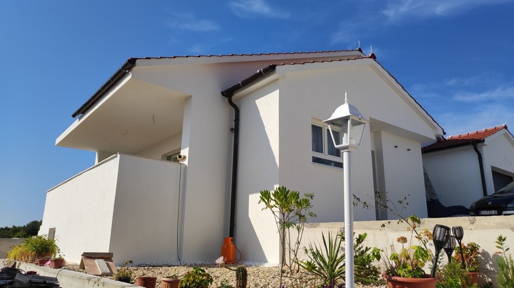 Boční pohled na dům na prodej ve Vodicích, Chorvatsko, s bílou fasádou a terasou.