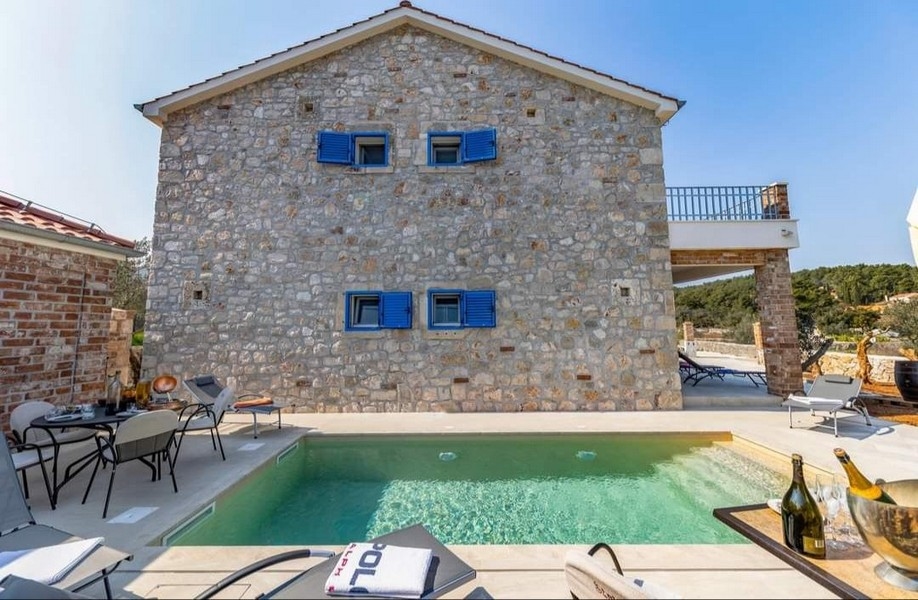 Zadní pohled na chorvatskou kamennou vilu na prodej s vlastním bazénem a grilem.