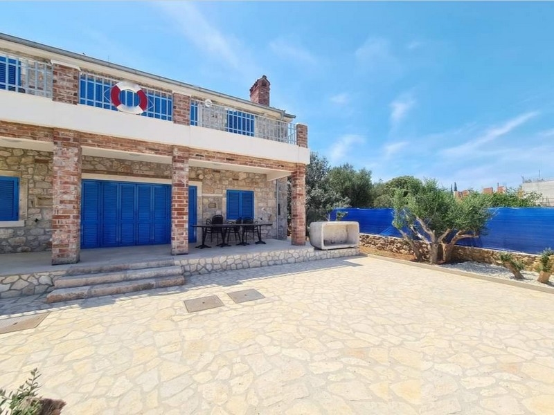 Čelní pohled na okouzlující kamenný dům na prodej v Chorvatsku s venkovním jídelním koutem.