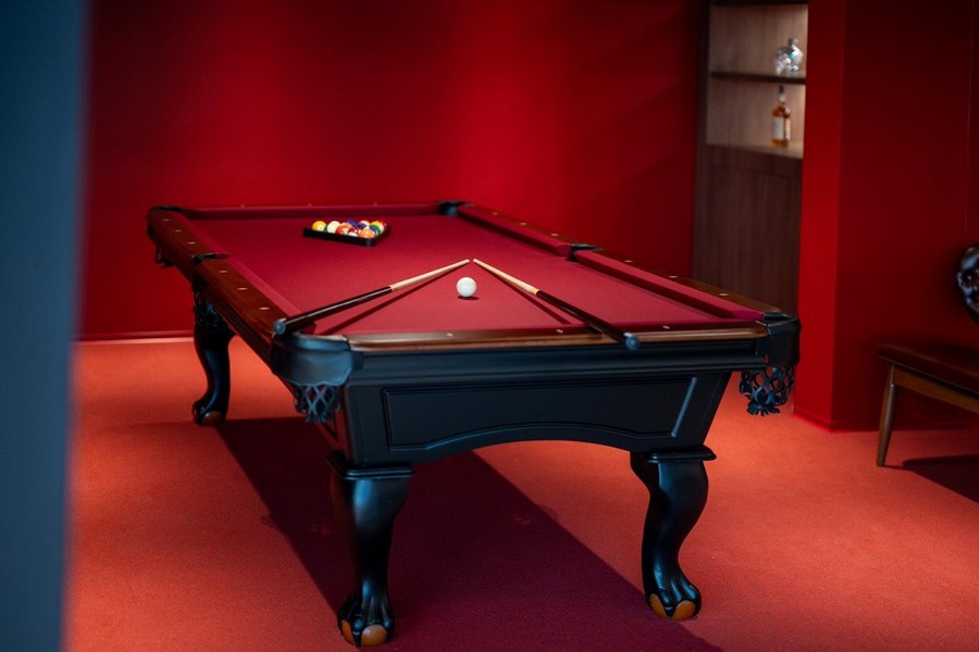 Kulečníková místnost ve vile v Chorvatsku na prodej s červenými stěnami a luxusním kulečníkovým stolem.