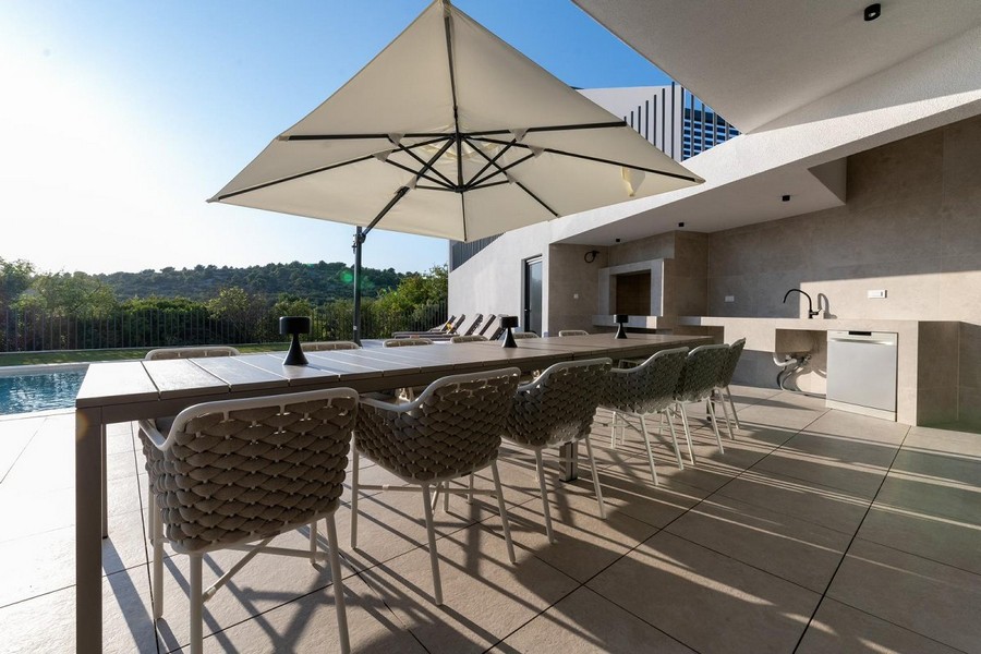 Elegantní venkovní terasa vily v Chorvatsku s jídelním stolem a kuchyní.