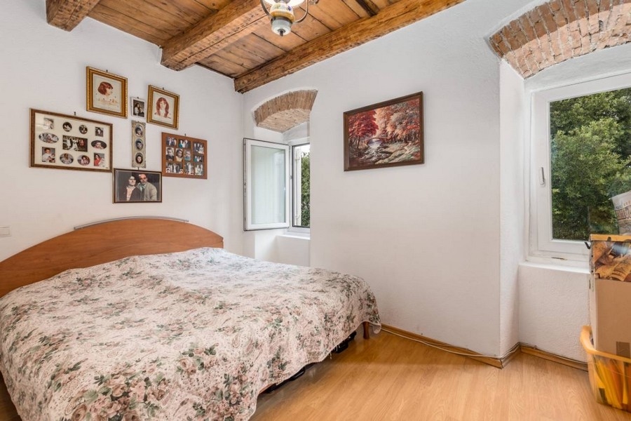 Ložnice nemovitosti v Chorvatsku s manželskou postelí a odhalenými trámy