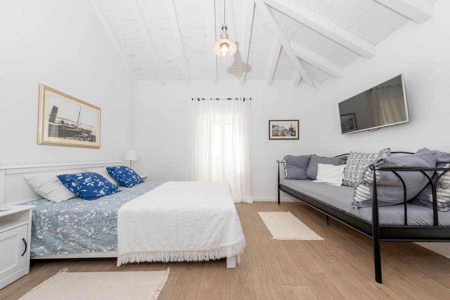 Útulná ložnice se šikmým stropem a přirozeným světlem v chorvatské nemovitosti