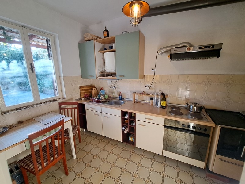 Tradiční chorvatská kuchyně s bílými skříňkami a oknem, součást nabídky nemovitostí od Panorama Scouting.