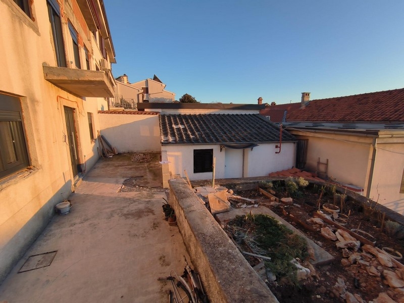 Dvorek nemovitosti v Chorvatsku s výhledem na sousední budovy a zahradu