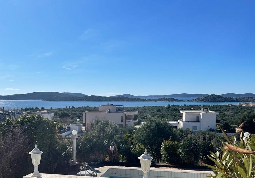 Široký úhel pohledu na bazén a vilu s výhledem na moře v dálce v Chorvatsku