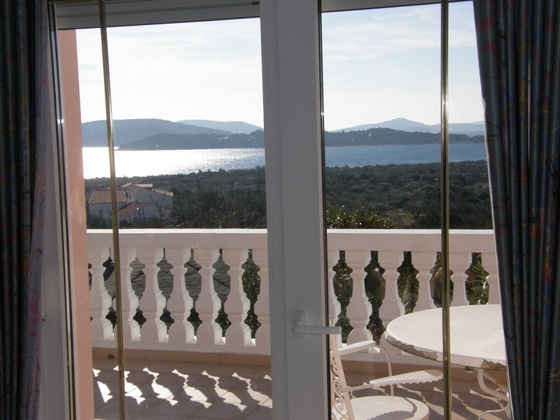 Výhled na moře z terasy chorvatské vily přes bílé zábradlí