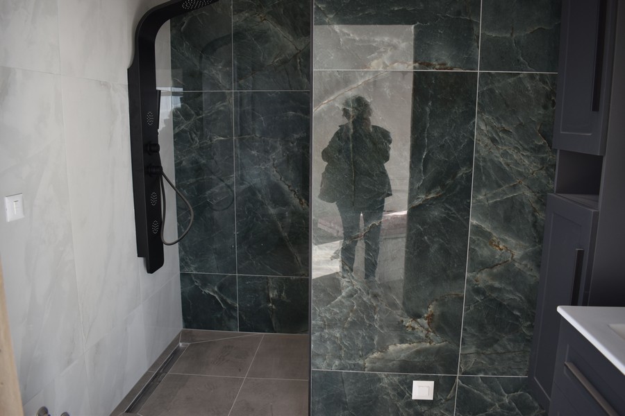 Elegantní sprchový kout s tmavými mramorovými obklady ve vile na prodej na ostrově Krk v Chorvatsku.