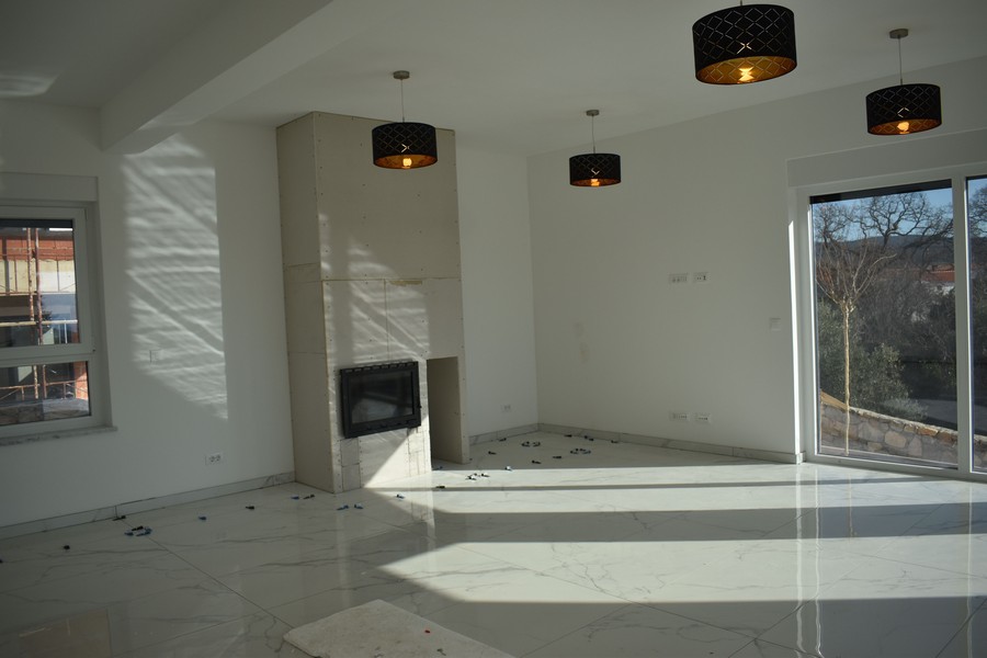 Vnitřní pohled na obývací pokoj s krbem a výhledem do přírody ve vile na Krku.