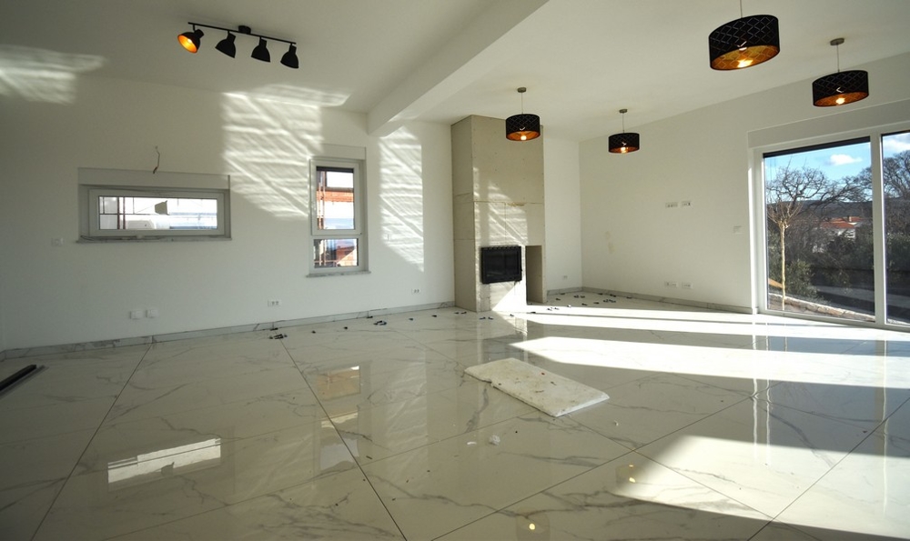 Slunný obývací pokoj s krbem a oknem v moderní vile na ostrově Krk.