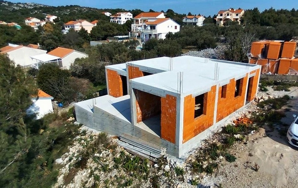 Detailní pohled na stavbu vily s odhalenými cihlovými zdmi a betonovými sloupy na prodej na ostrově Krk v Chorvatsku