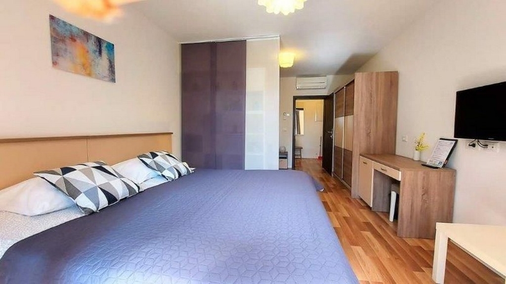 Ložnice v jednom ze tří apartmánů domu na prodej na Istrii, s velkou postelí, skříní a TV.