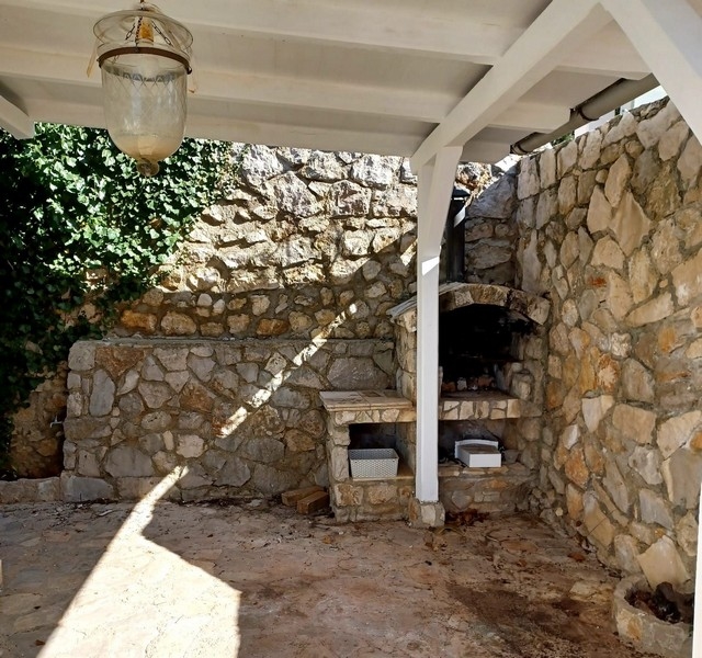 Venkovní kuchyně s tradiční kamennou pecí ve vile na prodej na ostrově Cres, Chorvatsko, pod bílou střechou