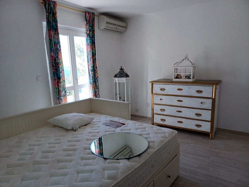 Ložnice s manželskou postelí a bílou komodou ve vile na prodej na ostrově Cres, Chorvatsko, s výhledem do přírody