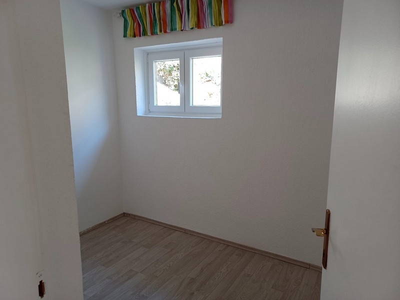 Jednoduchý, prázdný pokoj s oknem a dřevěnou podlahou ve vile na prodej na ostrově Cres v Chorvatsku