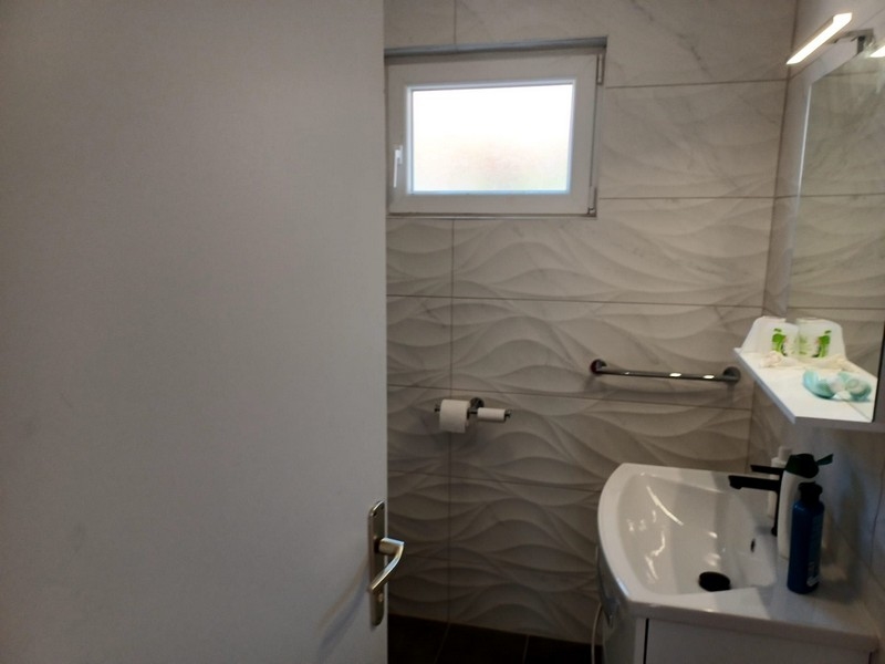 Koupelna s moderními vlnitými obklady a bílým umyvadlem ve vile na prodej na ostrově Cres v Chorvatsku.