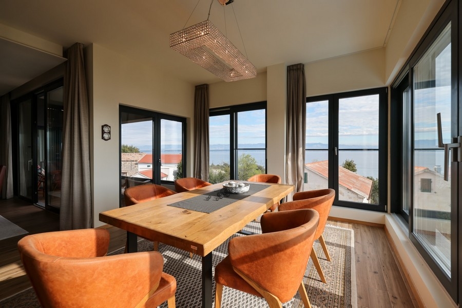 Jídelna s dřevěným stolem, oranžovými židlemi a výhledem na moře ve vile na prodej na Ugljanu.