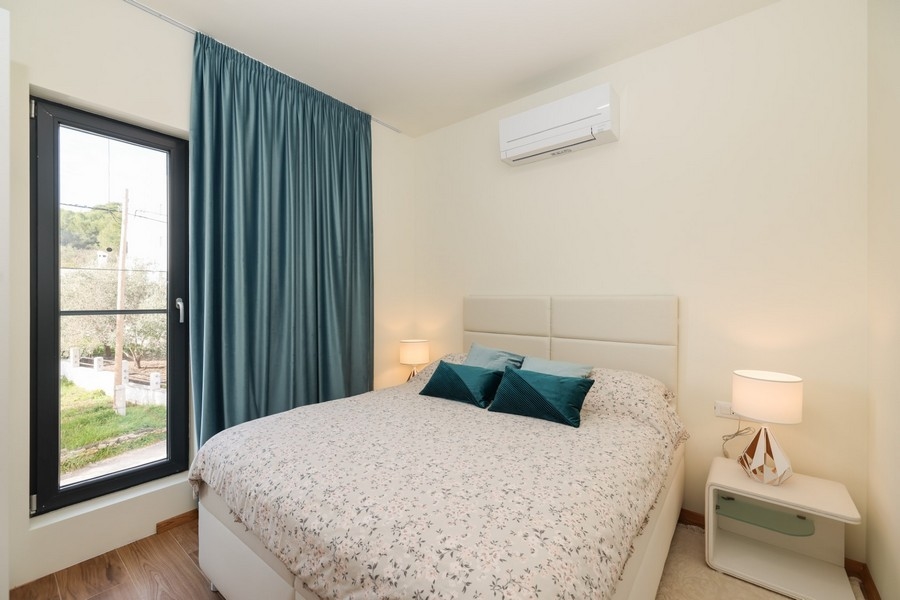 Dvoulůžkový pokoj se světlými barvami a výhledem z okna ve vile na ostrově Ugljan, nabízený k prodeji.