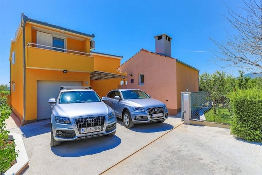 Přední vchod se dvěma zaparkovanými auty u bytového domu v Kaštel Lukšić, Chorvatsko