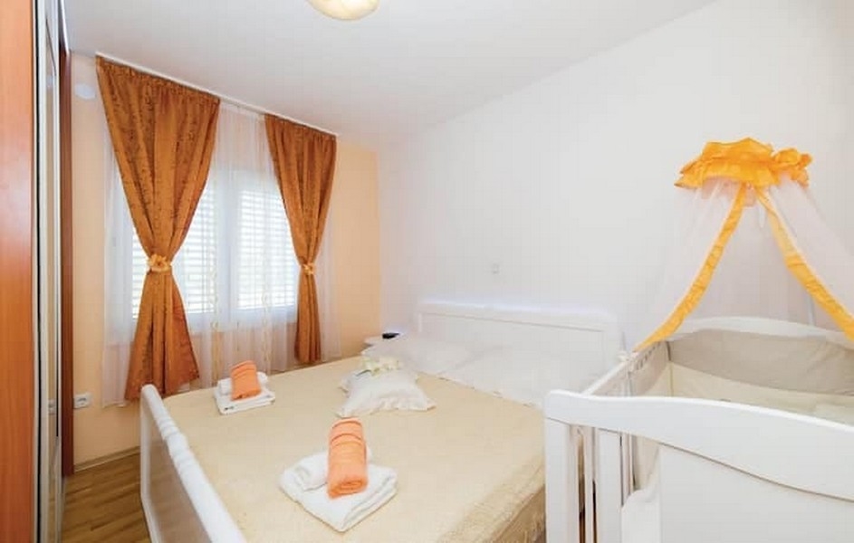 Ložnice s manželskou postelí a dětskou postýlkou ​​v apartmánovém domě v Kaštel Lukšić, Chorvatsko