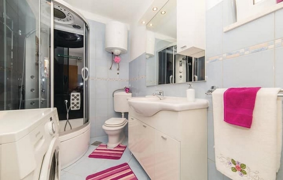 Koupelna se sprchovým koutem a pračkou v činžovním domě v Kaštel Lukšić, Chorvatsko