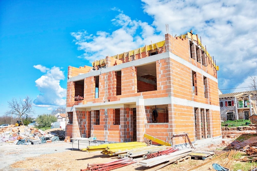 Plášť dvojdomu ve fázi výstavby s cihlami a lešením