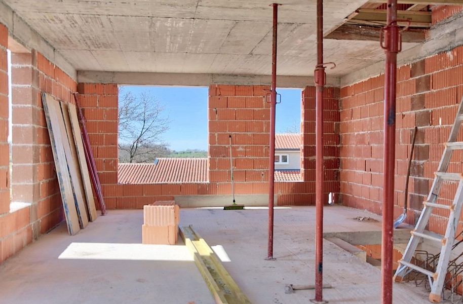 Vnitřní pohled na rozestavěný dvojdomek s výhledem ven velkým otvorem
