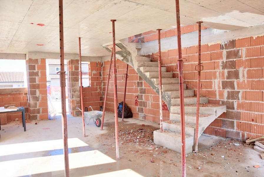 Vnitřní pohled na rozestavěný dvojdomek s betonovými schody a cihlovými zdmi