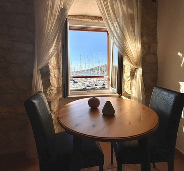 Pokoj se šikmým stropem a výhledem na přístav oknem v nemovitosti v Chorvatsku