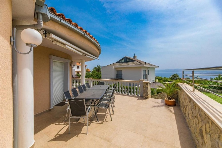 Velká terasa činžovního domu v Chorvatsku s dlouhým stolem a židlemi, výhled na moře