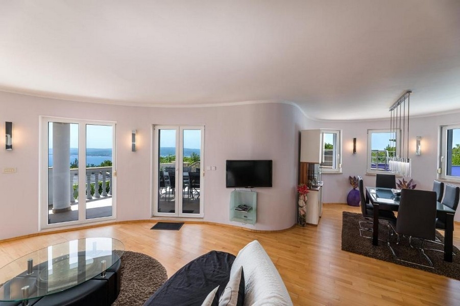 Obývací pokoj bytového domu v Chorvatsku s otevřeným půdorysem a přístupem na terasu s výhledem na moře