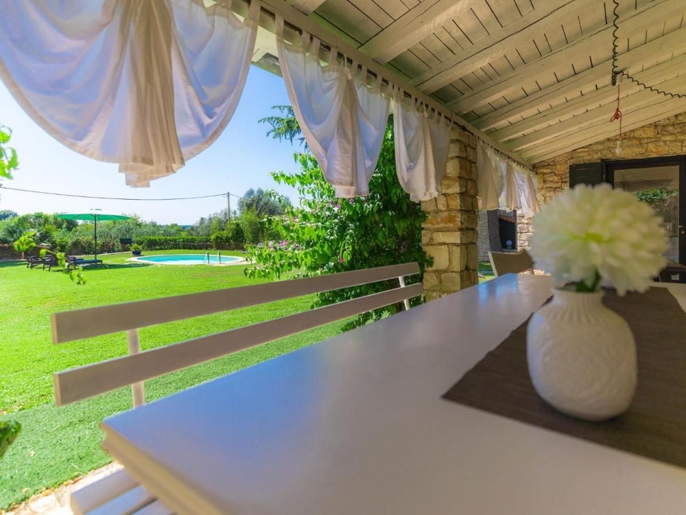 Krytá veranda s výhledem na bazén a udržovaný trávník, což je vlastnost nemovitostí v Chorvatsku