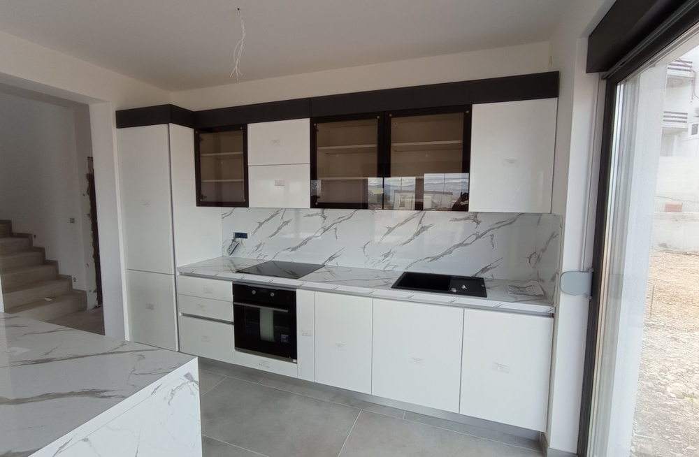 Vnitřní pohled na moderní kuchyni s bílým nábytkem v nemovitosti v Chorvatsku.