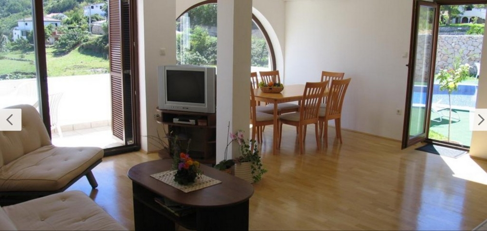 Vnitřní pohled na světlý obývací pokoj s dřevěnými podlahami a přístupem k bazénu, nemovitost Chorvatsko