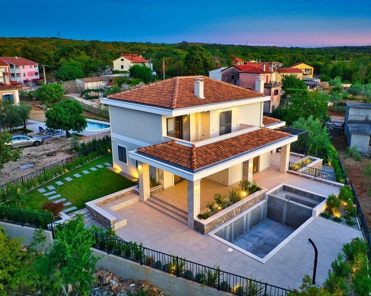 Nemovitost na ostrově Krk obklopená zelenou krajinou při západu slunce s osvětlenou zahradou