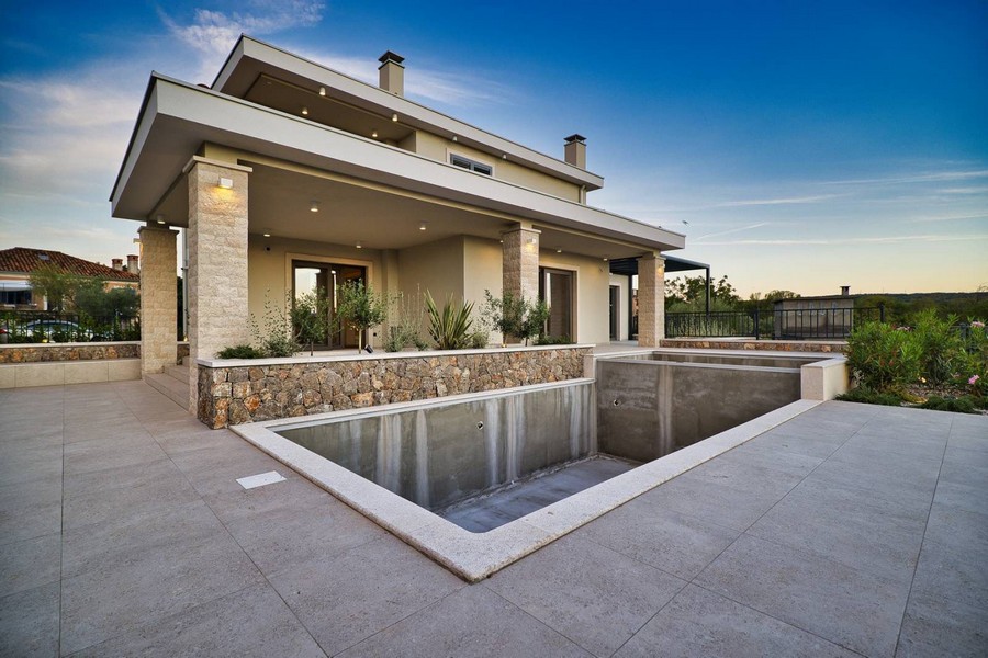 Boční pohled na nemovitost na ostrově Krk s prostornou terasou a nedokončeným bazénem při západu slunce