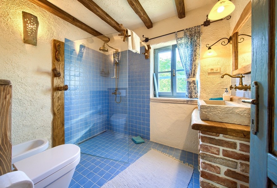 Koupelna s modrými obklady a přírodními dřevěnými prvky nabízí moderní komfort v nemovitosti na ostrově Krk.