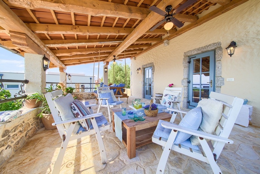 Příjemná terasa s rustikálním dřevěným nábytkem a dlážděnou podlahou, charakteristická pro nemovitost na ostrově Krk.