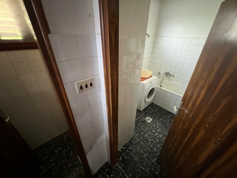 Jednoduchá koupelna s pračkou a toaletou ukazuje vybavení nemovitosti na ostrově Krk.