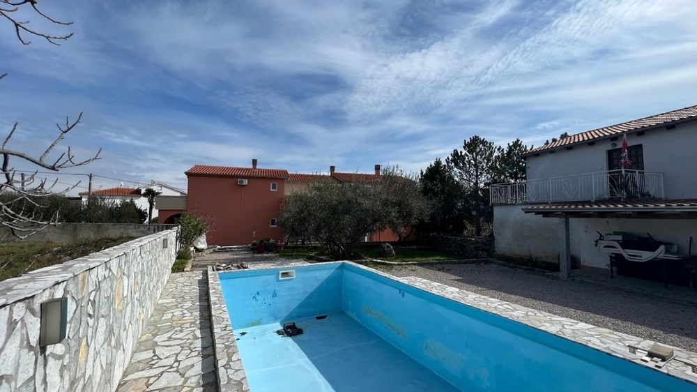 Nemovitosti Chorvatsko, město Krk, ostrov Krk Koupě činžovního domu, zadní pohled na dům s prázdným bazénem a zahradou