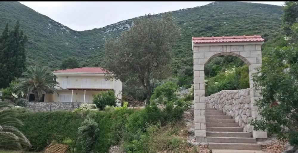 Pohled z vily na moře a vzdálené hory otevřenými prosklenými dveřmi, poloostrov Pelješac