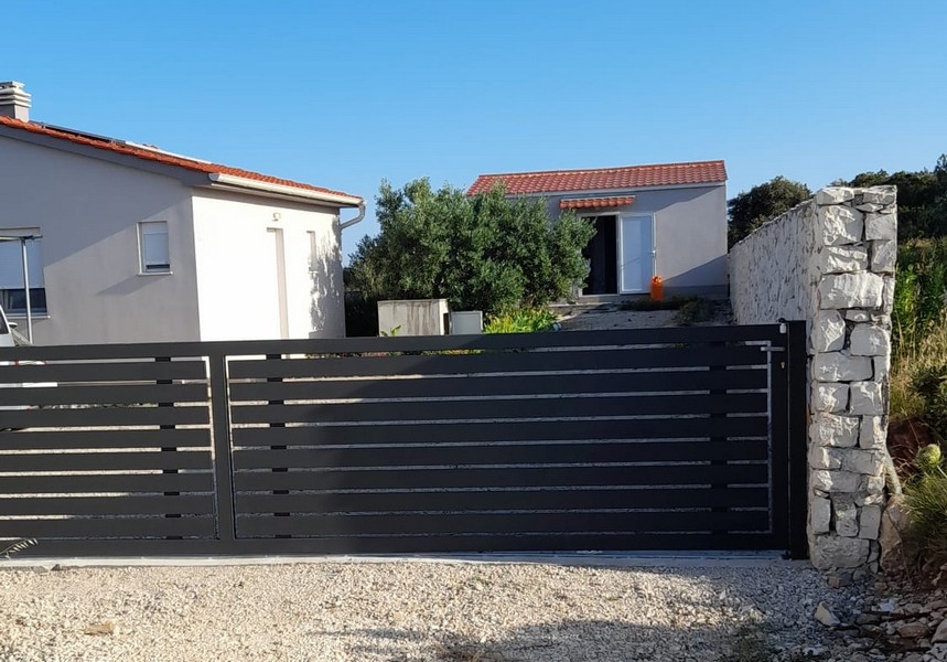 Jídelní kout se stolem a židlemi vedle kuchyně, s výhledem na moře přes skleněné dveře.