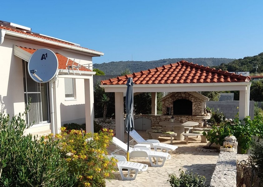 Obývací pokoj s pohovkou a televizí, sousedící s jídelnou.