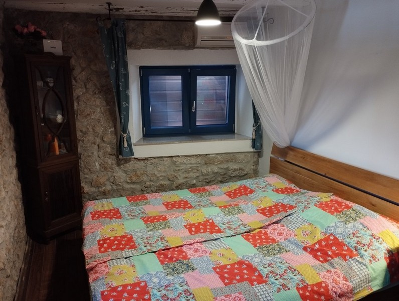 Útulná ložnice s barevnou přikrývkou, ideální pro každého, kdo si chce koupit dům v Chorvatsku.