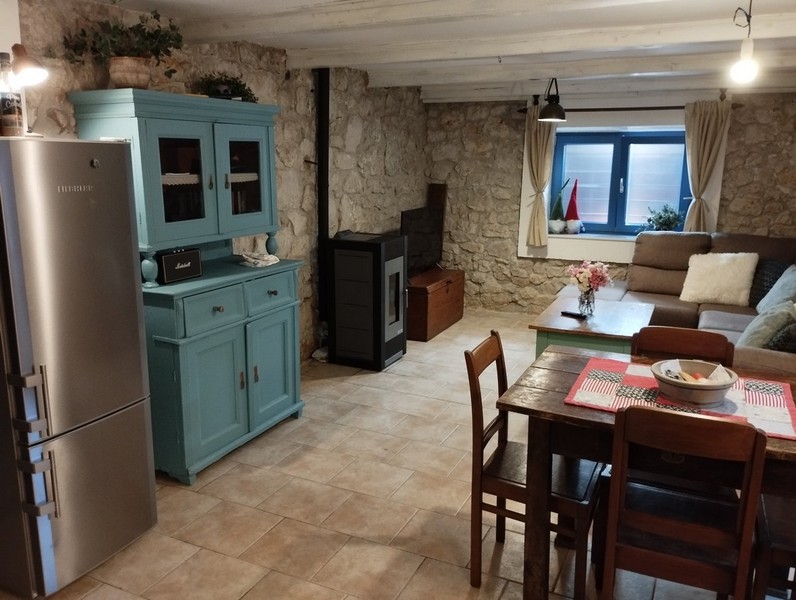 Otevřený obývací prostor s jídelním koutem a tradičním nábytkem, ideální pro koupi domu v Chorvatsku.