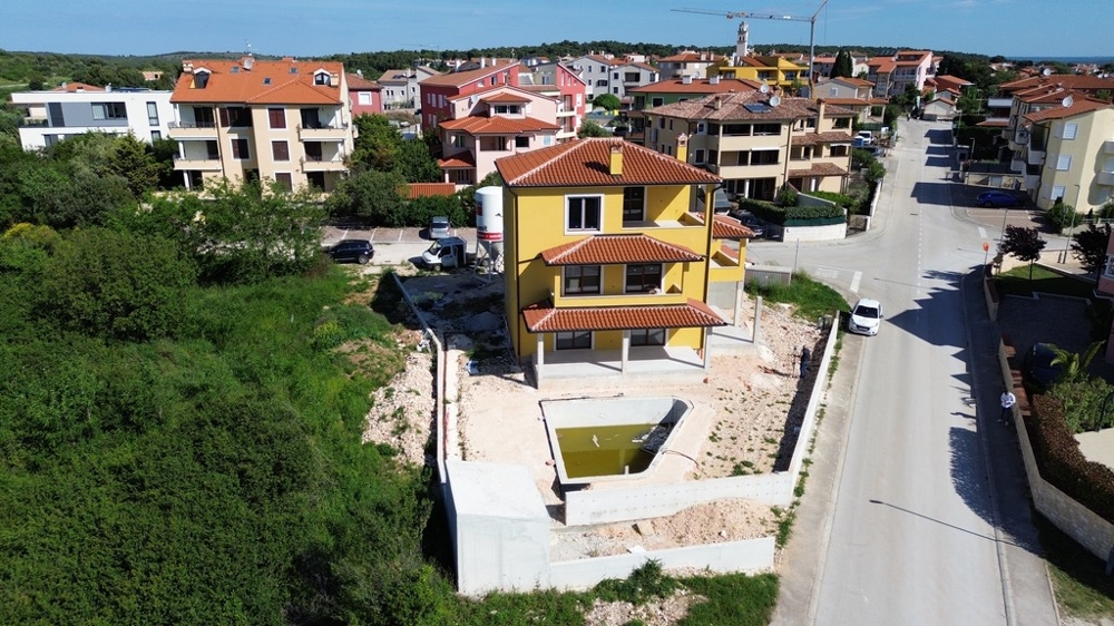 Prostorná vila v Chorvatsku ve fázi výstavby, obklopená moderními domy a zelenými plochami