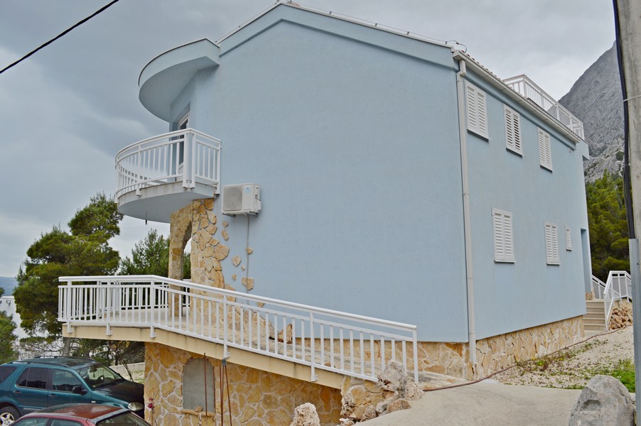 Modrý dům s kamennou zdí a balkonem